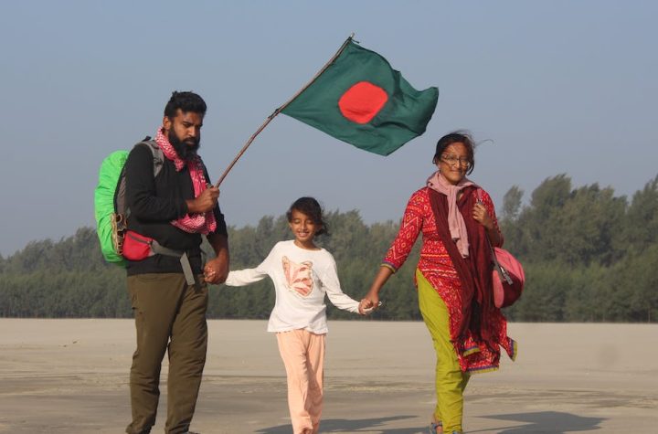family-with-a-bangladesh-flag-walking-by-the-beach