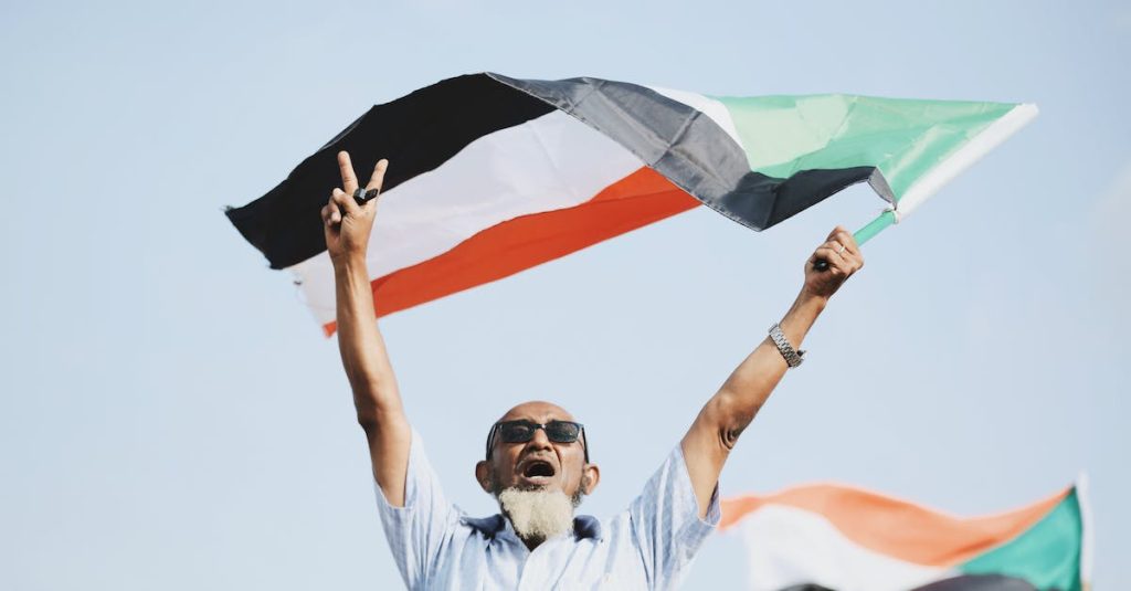 man-in-button-up-shirt-waving-sudanese-flag-in-victory