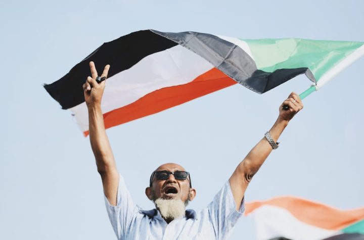 man-in-button-up-shirt-waving-sudanese-flag-in-victory