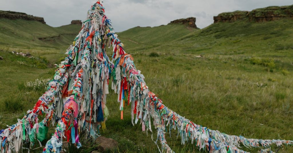 tibetan-bright-flags-located-in-field-with-fresh-green-grass-and-rocky-formations-under-cloudy-sky-1